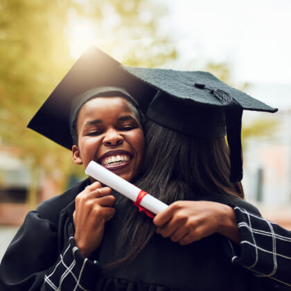 two women in graduation caps hugging