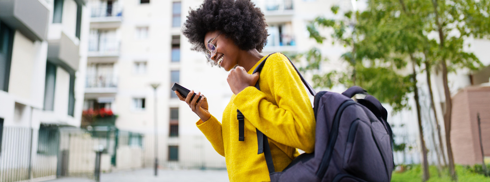 A young woman is walking happily while reading something in her phone