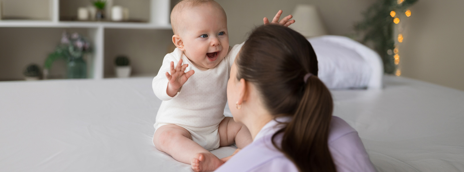 A mother and her new born baby playing on the bed