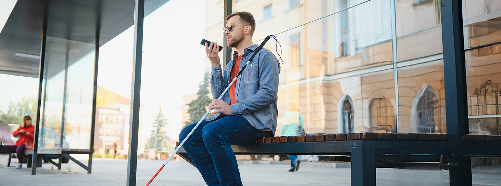 visually impaired man seated at a transit station