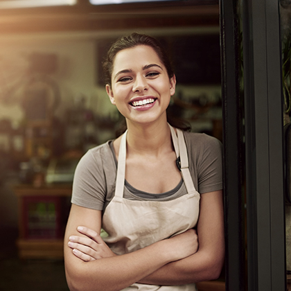 Image of a smiling shopkeeper resting against a doorframe