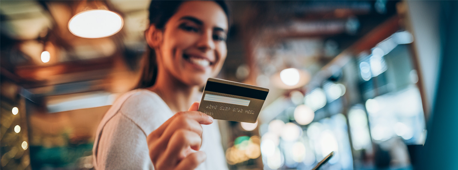 A woman smiles at the camera as she shows her credit card